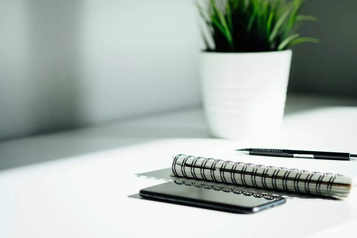 Téléphone, carnet à spirale et stylo sur un bureau blanc