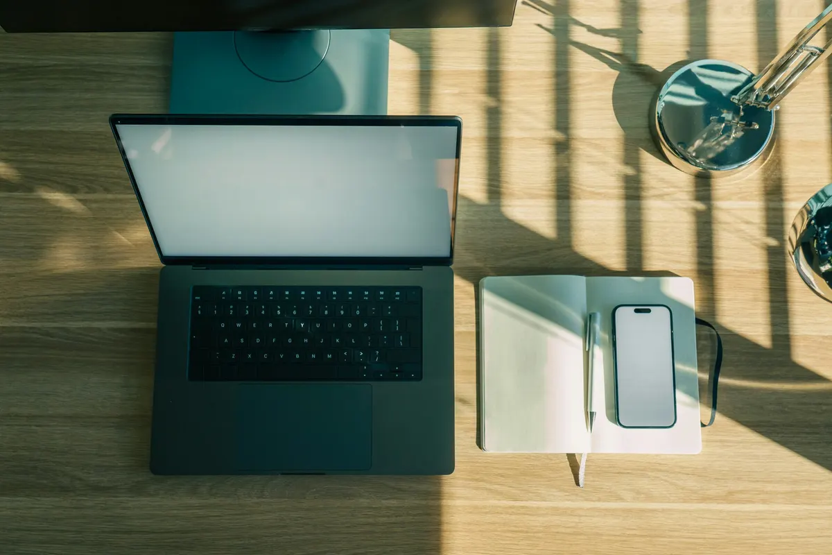 Ordinateur portable, téléphone et carnet sur un bureau en bois