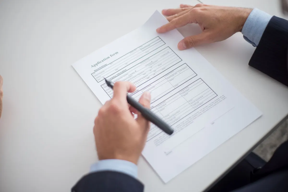 Mains remplissant un formulaire de demande