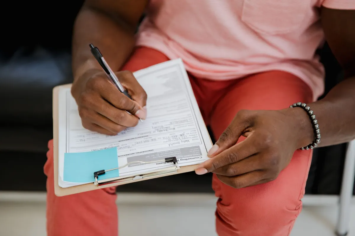Person filling in a form on a clipboard