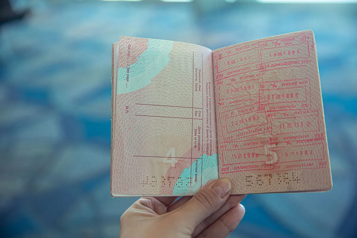 Main tenant un passeport ouvert sur des pages tamponnées