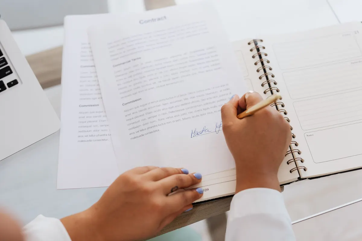 Mains signant un document posé sur un bureau