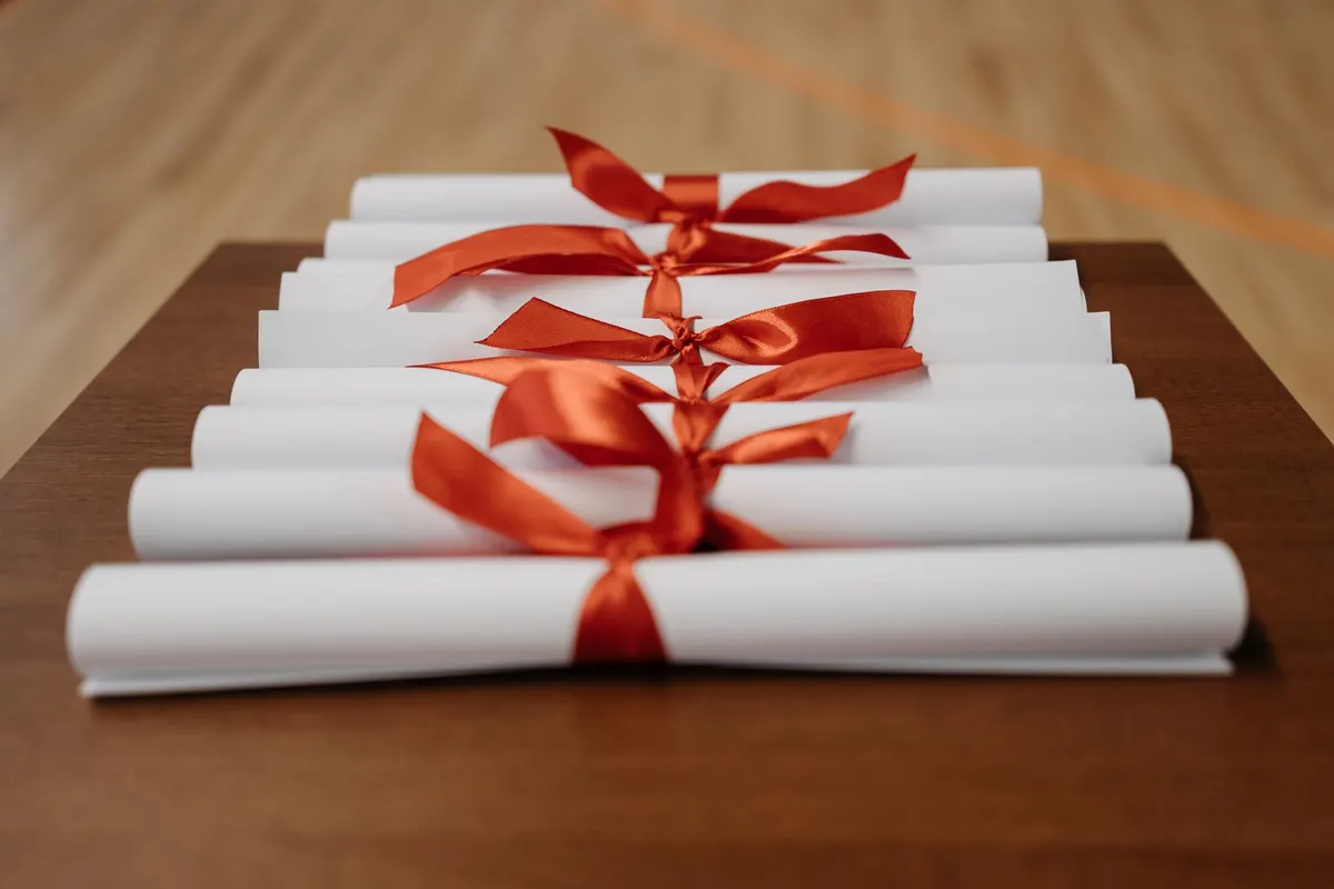 Diplômes roulés noués de rubans rouges sur une table en bois