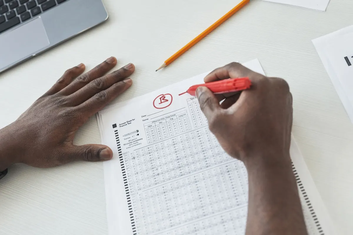 Mains corrigeant une feuille d'examen au feutre rouge