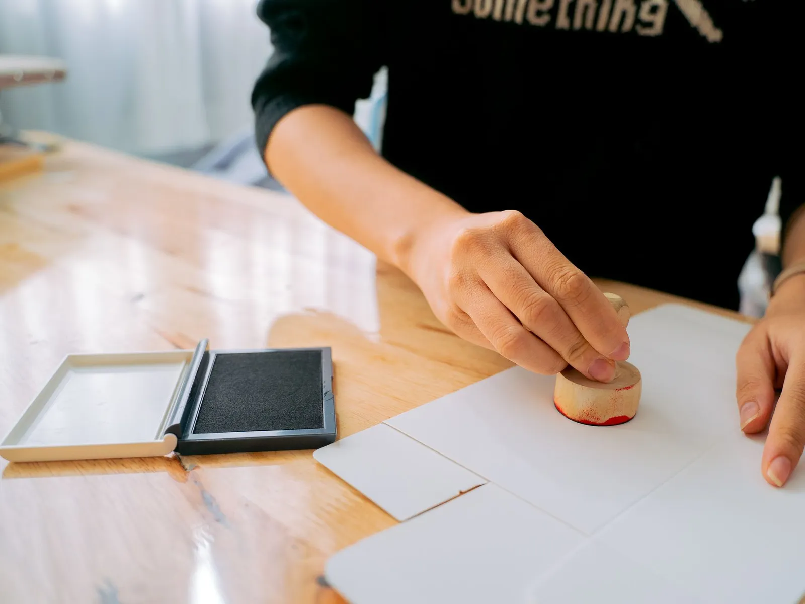 Hands pressing an ink stamp onto a document