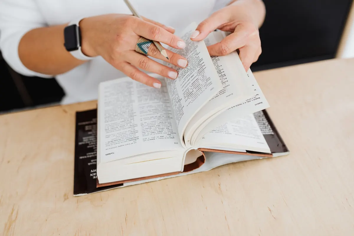 Mains feuilletant un dictionnaire sur une table