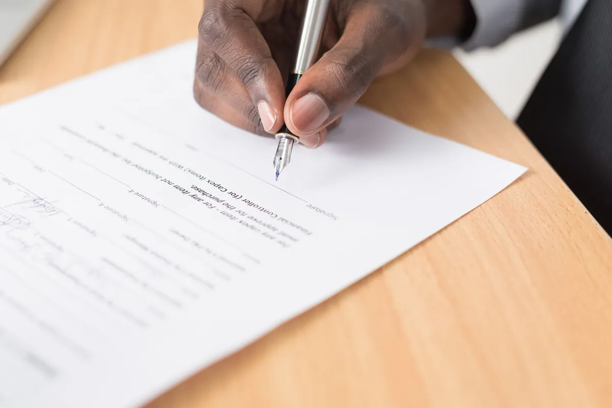Main signant un document au stylo plume